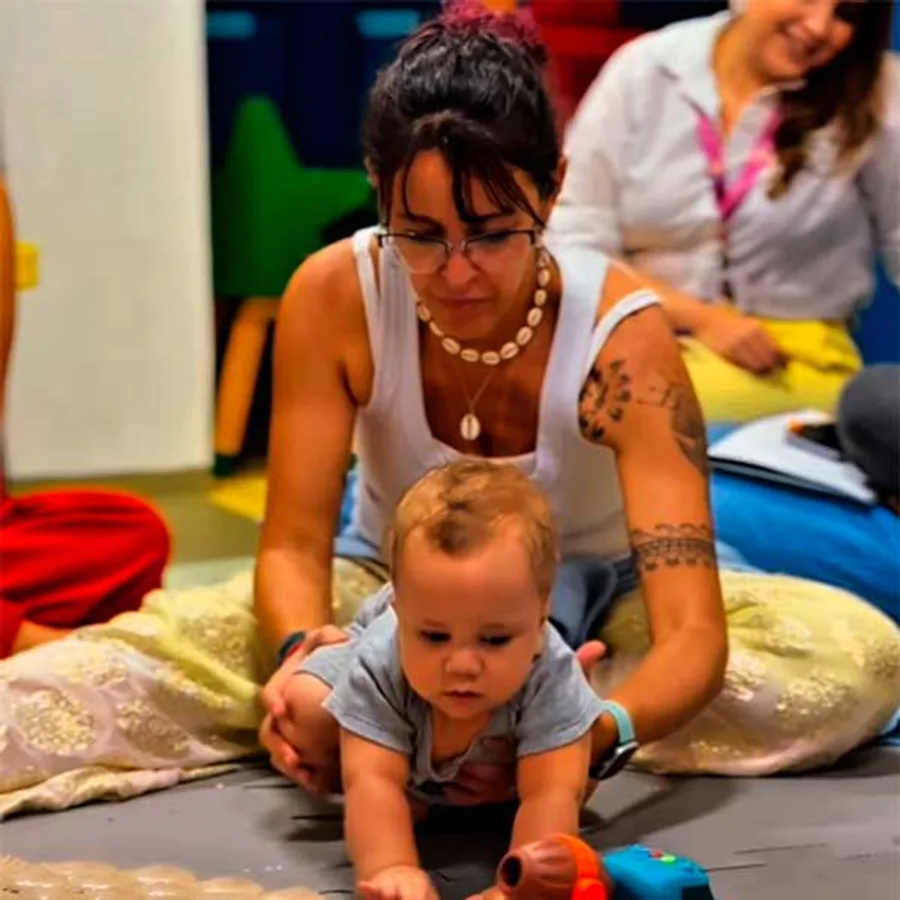 Profª Drª Dafne Herrero acompanhando um bebê que engatinha em direção a um brinquedo