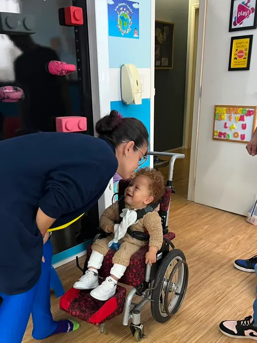 Dafne ajustando o posicionamento de uma criança em cadeira de rodas