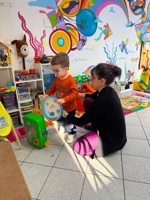 Dafne brincando com uma criança numa sala de atendimento colorida