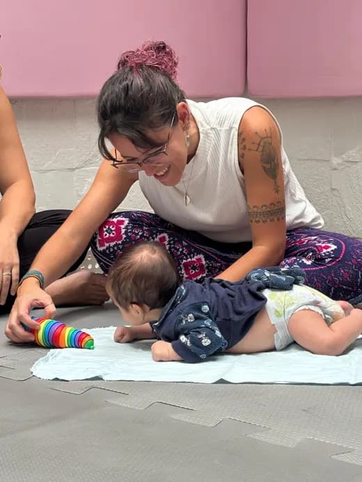 Dafne acompanhando um bebê deitado no tapete, de bruços
